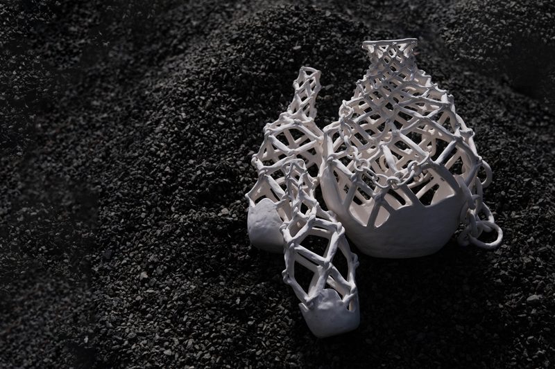 Porcelain vessels built as open lattice, on black gravel