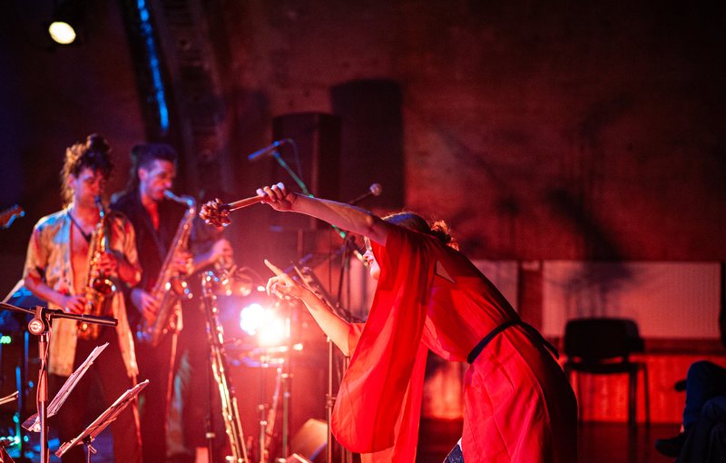 Mojca Zupančič conducting on stage in red light